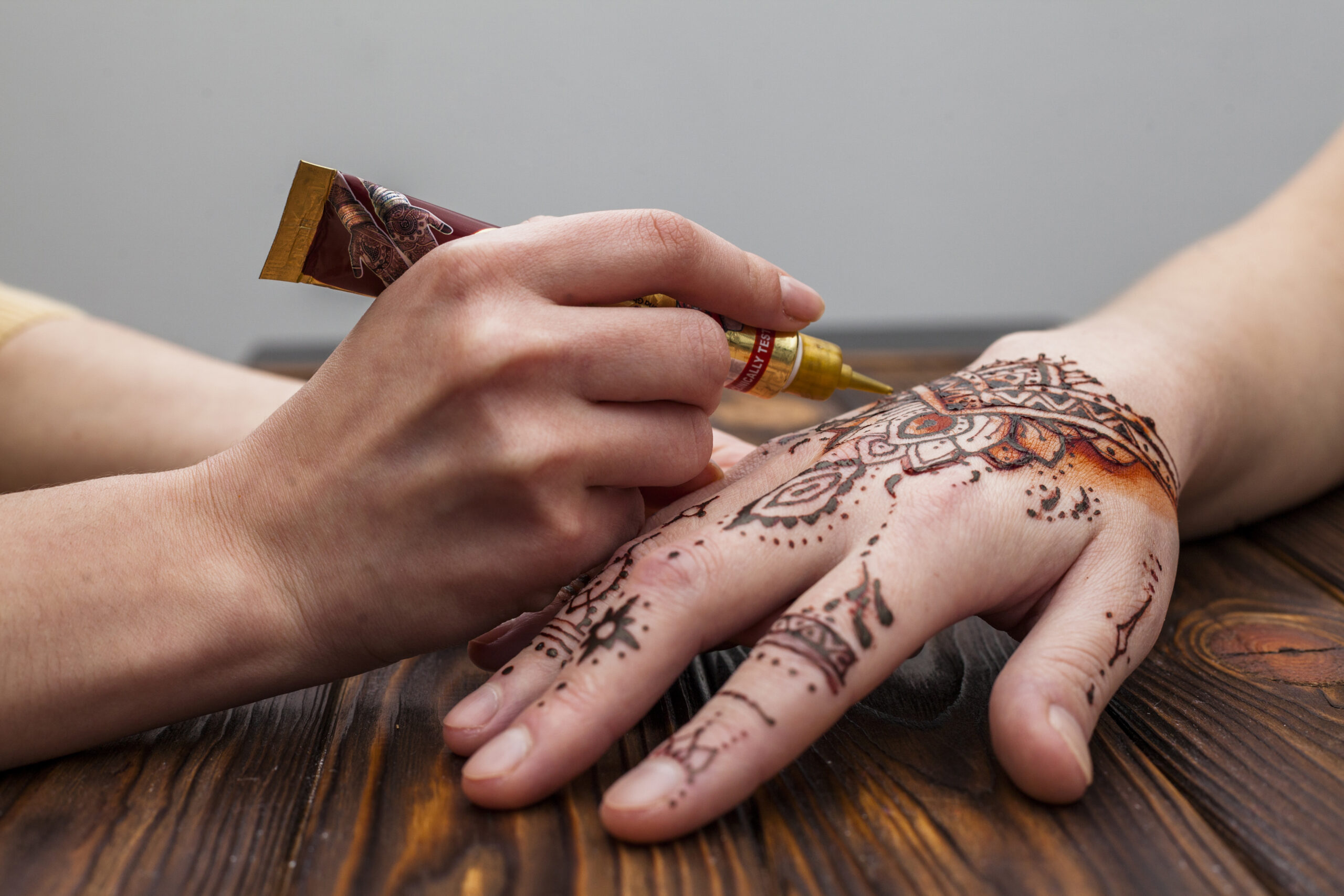 artist making mehndi womans hand table scaled